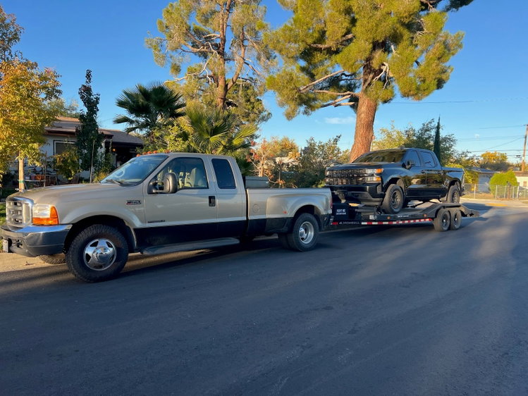 A Ford F-350 towing a black Silverado on our car hauler through a local neighborhood. Bring a tow-ready vehicle, and we’ll get you set up for the job.