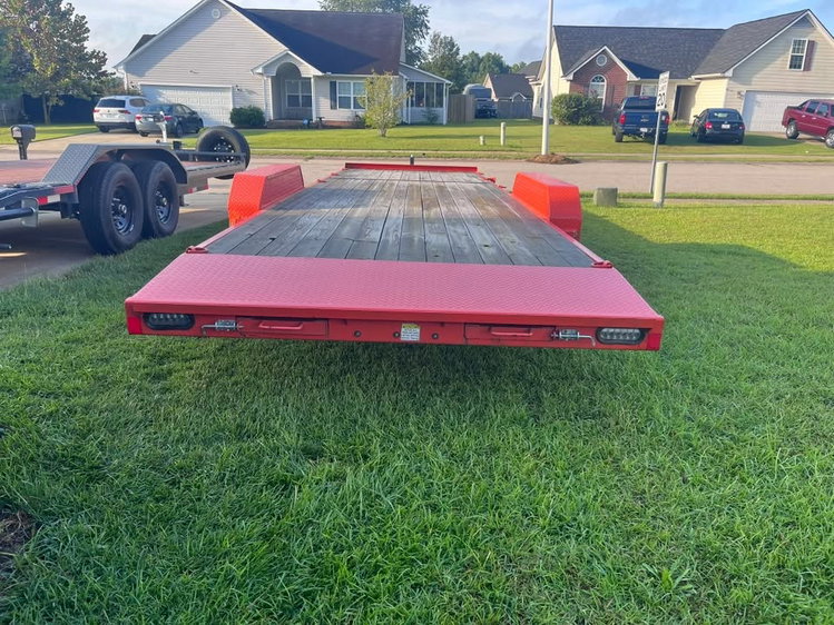 Orange tandem-axle car hauler trailer with wood deck and diamond-plate fenders, available to rent in Raeford, NC