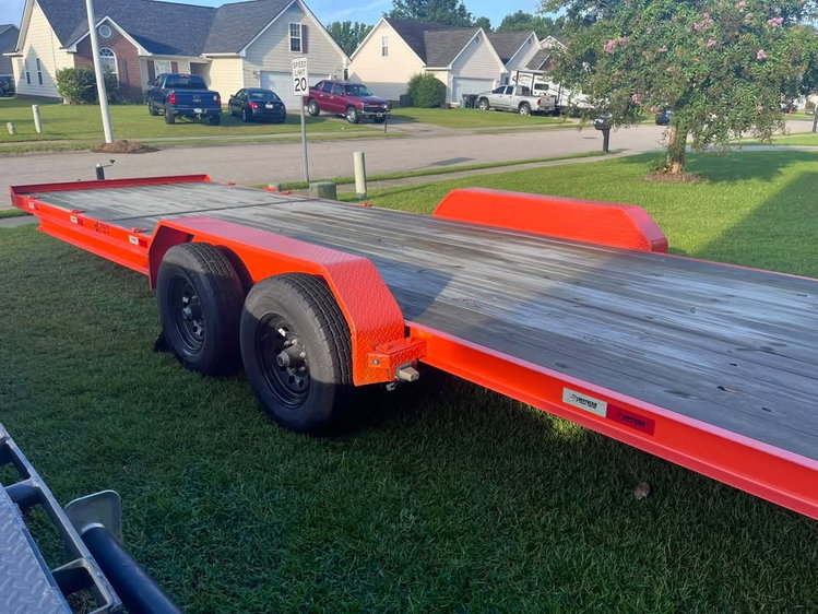 Orange tandem-axle car hauler trailer with wood deck and diamond-plate fenders, available to rent in Raeford, NC