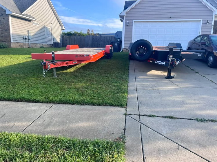 Two car hauler trailers available to rent from Carson Rental Co. in Raeford, NC, one orange and one black Lamar